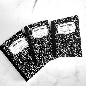 May include: Three black and white composition notebooks with the text "Sticker Book" on the front. Each notebook has a black spine and a white label with the text "16 sheets / 32 pages" and the dimensions "3.5 x 5.5 in".