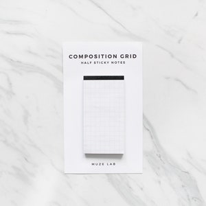 May include: White composition grid half sticky notes on a white marble background. The notes have a black top edge and the text "COMPOSITION GRID HALF STICKY NOTES" and "MUZE LAB" are printed on the packaging.
