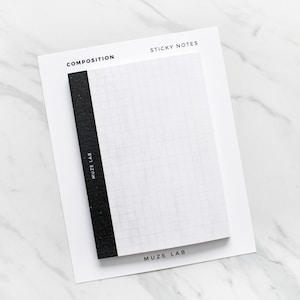 May include: A white sticky note pad with a black spine and grid pattern, labelled "COMPOSITION" and "STICKY NOTES." The brand name "MUZE LAB" is printed on the spine and bottom of the pad. The pad is on a white background.