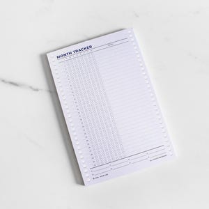 May include: A white paper month tracker notepad with dark blue text and lines. The header reads MONTH TRACKER, followed by a grid of numbered rows from 1 to 31 with circular checkboxes and a lined notes section. The bottom includes copyright text.