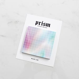 May include: A square sticky note pad with a colorful, grid-patterned design in shades of pink, blue, and green. The pad is on a white card with the word "prism" in a gothic font. The text "sticky notes" is below "prism".