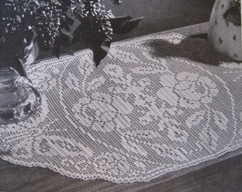 May include: A white crocheted table runner with a delicate floral pattern. The runner is made with a fine thread and has a lacy appearance.