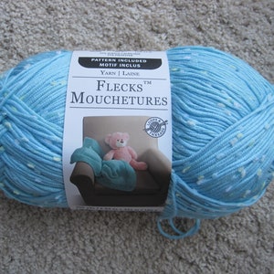 May include: A skein of light blue yarn with white flecks. The yarn label reads "Flecks Mouchetures" and "Loops & Threads" with a pattern included motif.