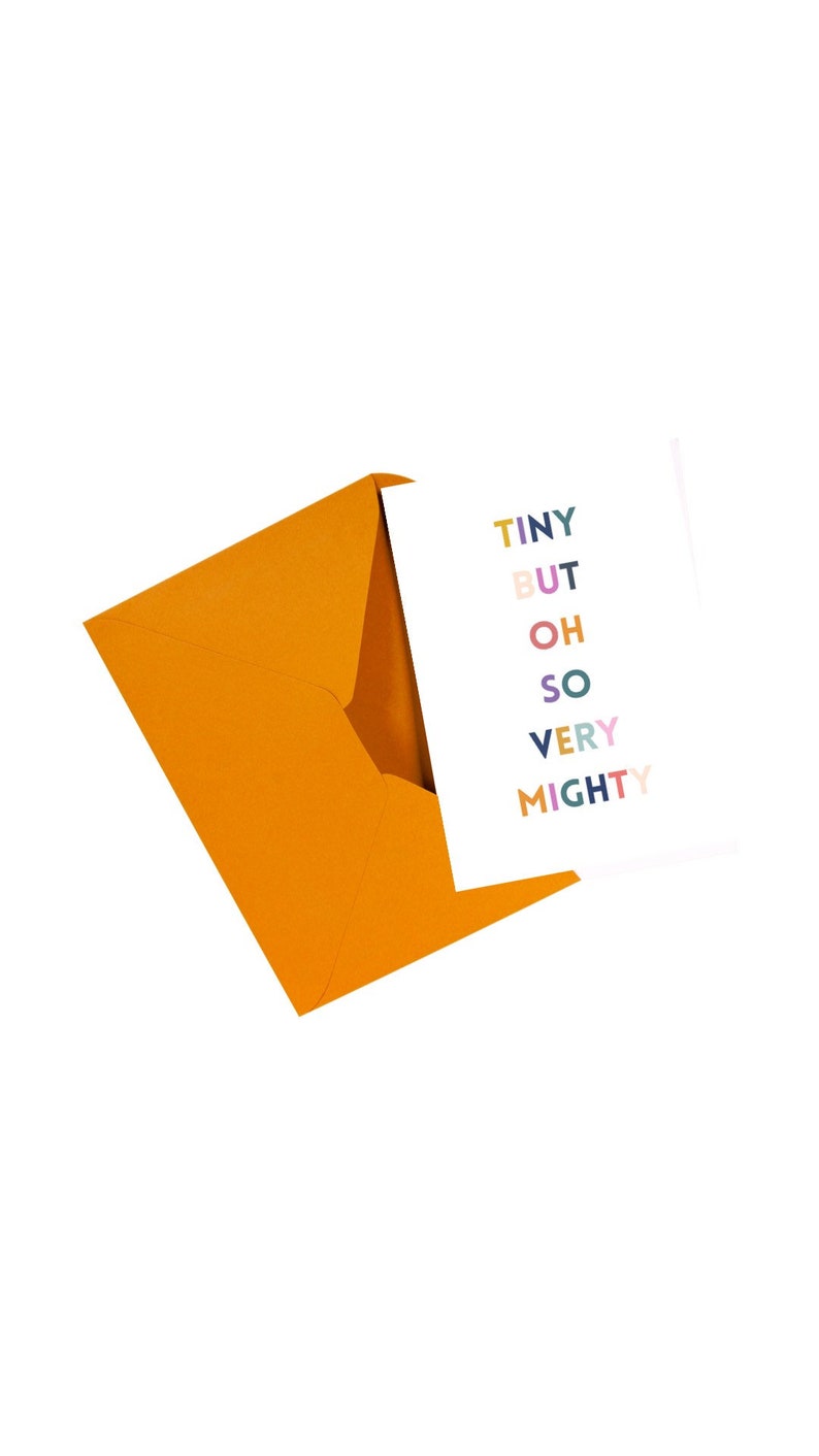 May include: A white card with the words "TINY BUT OH SO VERY MIGHTY" in various colours, emerging from an orange envelope. The card and envelope are set against a white background.