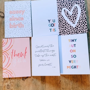May include: A selection of greeting cards with different designs and text. One card says "sassy since birth" on a polka dot background. Another says "You Got This." Other cards say "thank you," and "Tiny but oh so very mighty."