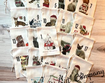 May include: A set of twenty-four off-white fabric drawstring bags for an advent calendar, each featuring a unique cat illustration and a number from 1 to 24. Some bags display cats wearing Santa hats, scarves, or sweaters, with text like Meowy Christmas.