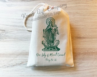 May include: A white drawstring bag with a green image of Our Lady of Mount Carmel and the text "Our Lady of Mount Carmel Pray For Us".