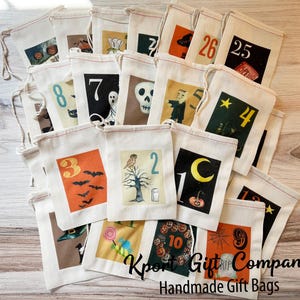 May include: A selection of cream-coloured Halloween-themed gift bags, each with a unique illustration and number. Designs include bats, ghosts, and pumpkins. The bags are made of canvas and have drawstring closures. The text "Kport Gift Company Handmade Gift Bags" is visible.