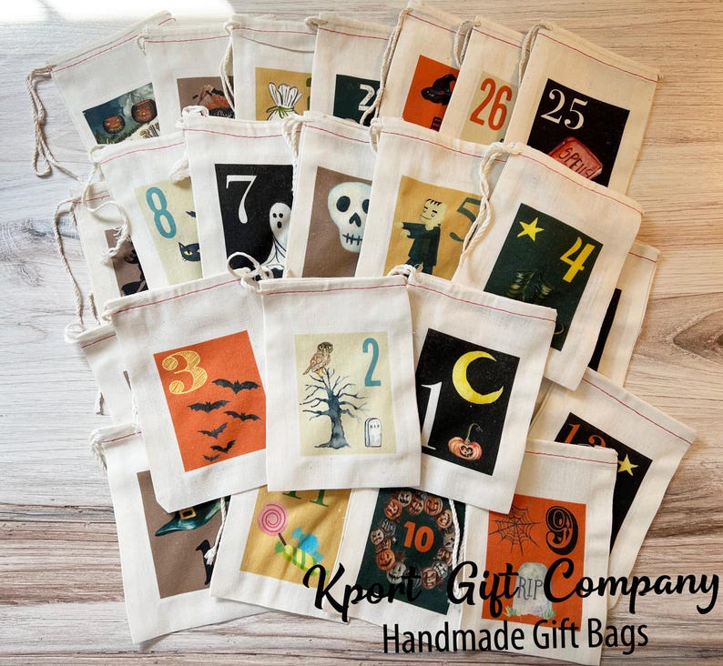May include: A selection of cream-coloured Halloween-themed gift bags, each with a unique illustration and number. Designs include bats, ghosts, and pumpkins. The bags are made of canvas and have drawstring closures. The text "Kport Gift Company Handmade Gift Bags" is visible.