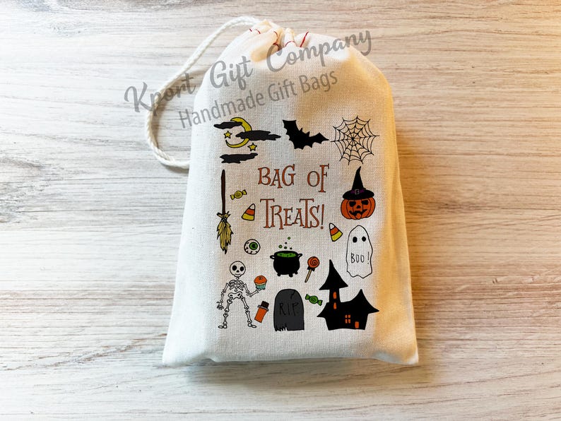 May include: A cream-colored Halloween-themed gift bag with a drawstring closure. The bag is decorated with various Halloween icons, including a bat, spiderweb, pumpkin, ghost, and the text "BAG OF TREATS!"