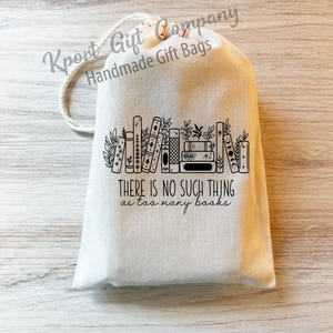 May include: A white cotton drawstring bag with a black and white illustration of a stack of books and the text "THERE IS NO SUCH THING as too many books".