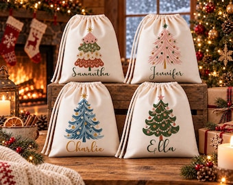 May include: Four off-white drawstring gift bags featuring printed Christmas tree illustrations and personalized names. The top left bag shows a tree with Samantha, top right Jennifer, bottom left Charlie, and bottom right Ella.