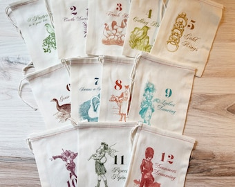 May include: A set of twelve off-white cotton drawstring bags, each printed with a number from one to twelve and corresponding illustrations and text from the Twelve Days of Christmas, featuring various colored inks including green, red, blue, and gold.