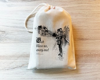 May include: A cream-colored fabric drawstring pouch featuring a black ink illustration of a person carrying a child on their shoulders in a street scene. The text reads God bless us, every one! Tiny Tim A Christmas Carol in black lettering.