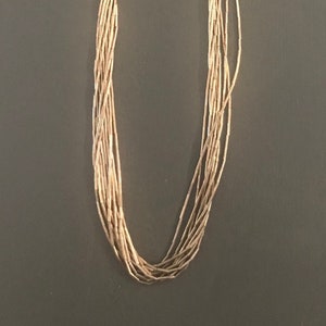 May include: A long silver necklace with multiple strands of small beads. The necklace is made of sterling silver and has a simple design.