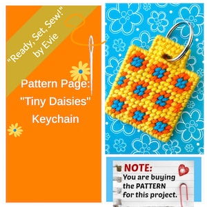 May include: A handmade keychain with a yellow daisy pattern, featuring orange and blue accents. The keychain is attached to a silver metal ring. The image also includes text that reads "Ready, Set, Sew!" and "Tiny Daisies Keychain".