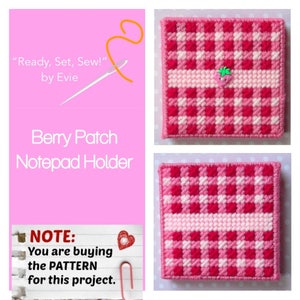 May include: A pink notepad holder with a red and white gingham pattern. The notepad holder has a light pink stripe across the middle and a small strawberry embellishment. The text "Berry Patch Notepad Holder" is visible.