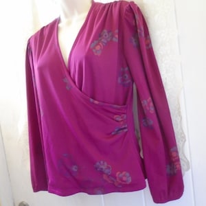 May include: A long-sleeved, magenta blouse with a wrap-style neckline and a floral print in shades of purple, pink, and orange.