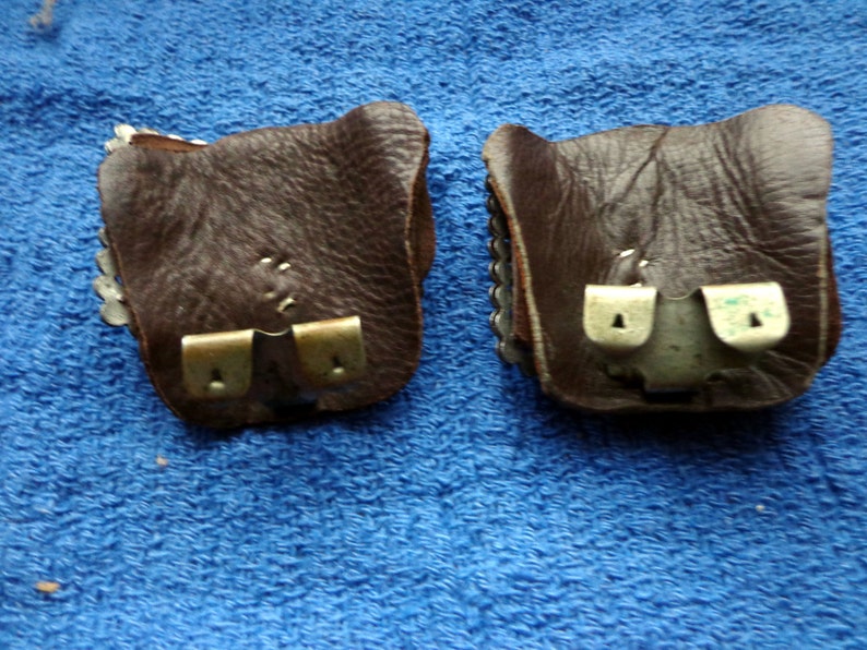 Puede incluir: Dos bolsas de cuero marr&oacute;n con cierres met&aacute;licos. Las bolsas tienen un dise&ntilde;o decorativo en la parte delantera.