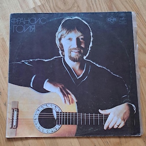 Puede incluir: Portada de álbum con un hombre con barba sosteniendo una guitarra. El título del álbum está en cirílico. El hombre lleva un suéter negro. La guitarra es de color marrón claro.