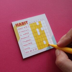 May include: A habit tracker with the word "HABIT" at the top. The tracker includes daily goals: wake up at 7, take vitamins, drink 2L water, workout, journal, meditate, read, and bed by 10:30. A yellow marker is used to fill in the tracker.