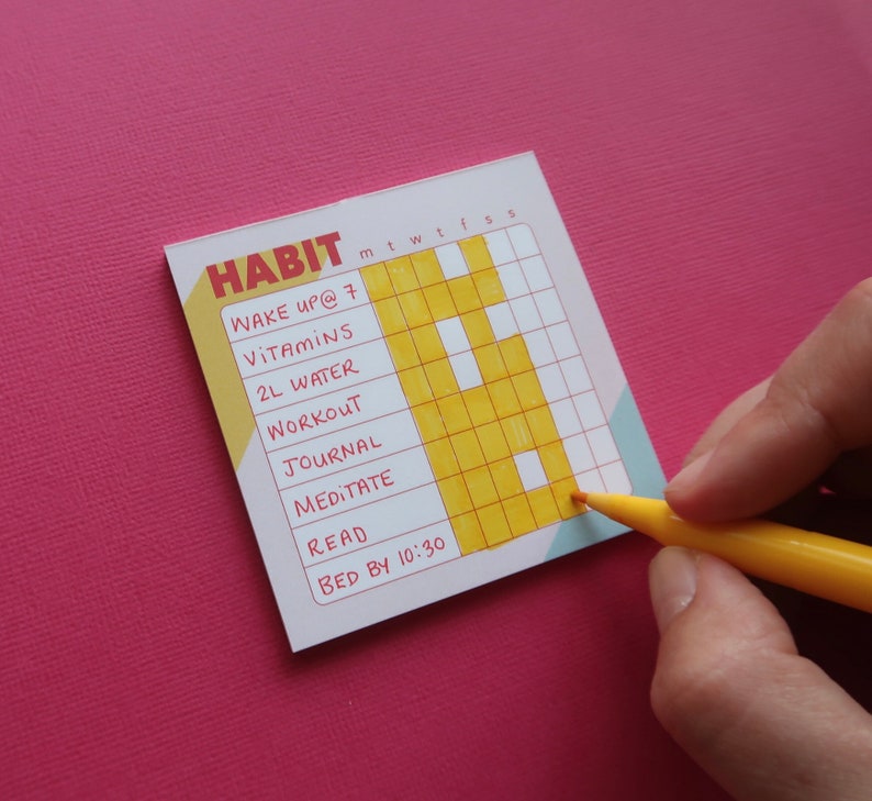 May include: A habit tracker with the word "HABIT" at the top. The tracker includes daily goals: wake up at 7, take vitamins, drink 2L water, workout, journal, meditate, read, and bed by 10:30. A yellow marker is used to fill in the tracker.