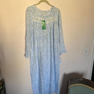 May include: A light blue nightgown with a floral print and white lace trim. The nightgown has long sleeves and a button-up front. The tag on the nightgown reads "Willamette Valley".
