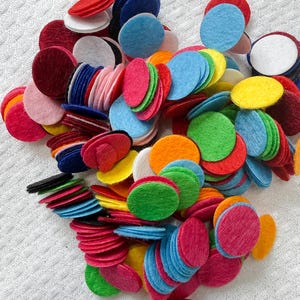 May include: A pile of colorful felt circles in various shades of red, pink, blue, green, yellow, orange, and white. The felt circles are stacked and scattered, creating a vibrant and textured display. Ideal for craft projects.