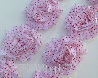 May include: White fabric flower trim with red polka dots. The trim is made of multiple layers of fabric and has a ruffled edge.