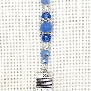 May include: A silver charm with a blue and clear crystal bead chain and a silver charm that says "No. 10 Silk Cured".