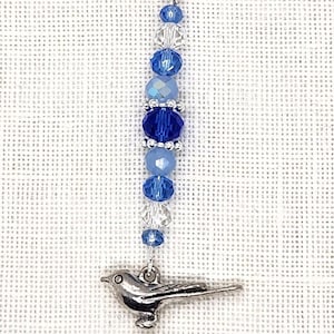 May include: A silver charm with a blue crystal bead and a silver bird charm. The charm is attached to a silver lobster clasp.