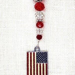 May include: A silver charm with a red, white, and blue beaded chain and a small American flag charm.