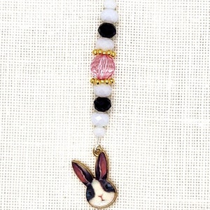 May include: A white and black bunny charm with pink and black beads on a silver chain with a silver clasp.