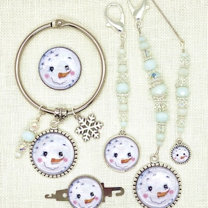 May include: A collection of winter-themed jewelry and accessories featuring a snowman design. Includes a silver-tone bracelet, charms, keychains, and beaded accents. The snowman has a carrot nose, rosy cheeks, and a smiling face.