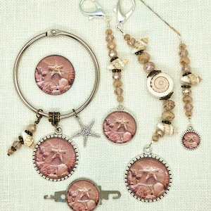 May include: A collection of beach-themed jewelry and accessories. The items include a circular bracelet, charms, and stitch markers. The charms and stitch markers feature a starfish and seashells design. The accessories are adorned with beads and shells.