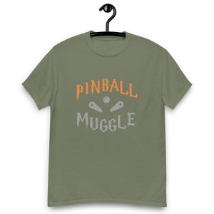 May include: A green t-shirt with the text "Pinball Muggle" in orange and gray lettering. The text is stylized to look like a pinball machine.