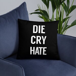 May include: Black throw pillow with white text that reads "DIE CRY HATE".