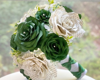 May include: A bouquet of green and white paper roses. The green roses are made from paper and have a pearl center. The white roses are made from pages of a book. The bouquet is tied with a green ribbon.