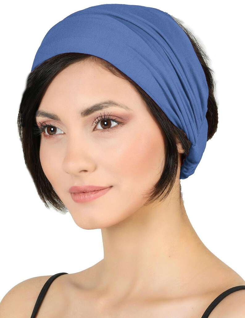 May include: A blue headband made of soft fabric. The headband is wrapped around the head. The colour is a muted blue, and the fabric appears to be stretchy and comfortable. This accessory is suitable for various hairstyles.