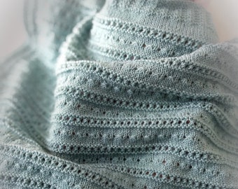May include: A soft, light blue knitted baby blanket with a delicate openwork pattern.