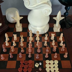 May include: A wooden chessboard with white and brown chess pieces set up for a game. There are also red and white checkers pieces, two dice, and a die with the number 64 on it.