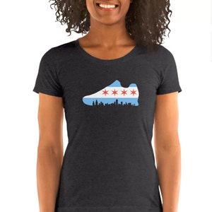 May include: A dark heather grey t-shirt with a graphic of a running shoe in the shape of the Chicago flag. The shoe is outlined in black and the flag is blue, white, and red with four red stars.