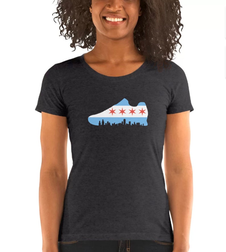 May include: A dark heather grey t-shirt with a graphic of a running shoe in the shape of the Chicago flag. The shoe is outlined in black and the flag is blue, white, and red with four red stars.