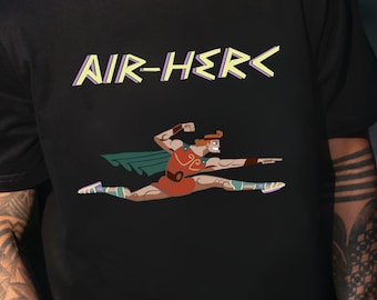 May include: Black t-shirt with a graphic of a cartoon superhero in a red and green costume, kicking with the text "AIR-HERC" above the image.