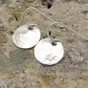 May include: A pair of silver hammered disc earrings with a simple hook closure.