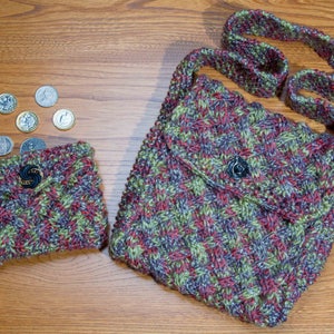 May include: A knitted purse and wallet set in a woven pattern of red, green, and purple. The purse has a flap with a button closure and a long strap. The wallet has a zip and a button closure. The set is handmade.