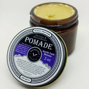 May include: A 2 ounce jar of North Fork Breeze pomade by Roosevelt Grooming Co. The jar is brown glass with a black and white label. The label has the company logo, the product name, and the ingredients. The pomade is natural and water-based.