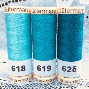 May include: Three spools of Gütermann thread in shades of blue. The spools are labeled with the numbers 618, 619, and 625. Each spool has 100 meters or 110 yards of thread.