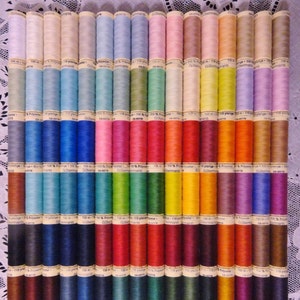 Puede incluir: Una colección de 40 carretes de hilo en varios colores, incluyendo rosa, azul, verde, amarillo, naranja, rojo, marrón y morado. Cada carrete está etiquetado con "Gütermann" y tiene una etiqueta blanca con texto negro.