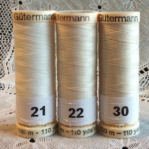 May include: Three spools of white Gütermann thread, labeled with numbers 21, 22, and 30. Each spool is 110 yards long.